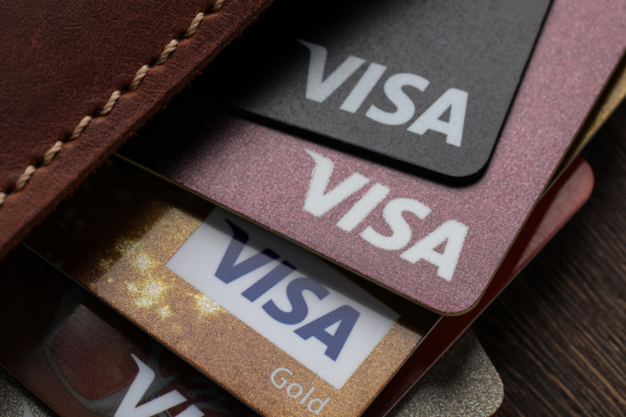 4 Visa credit cards sticking out of brown leather wallet
