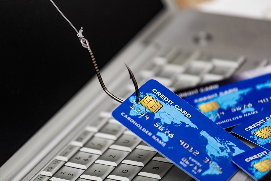 Fishing Hook on Credit Card Resting on Top of Laptop Keyboard